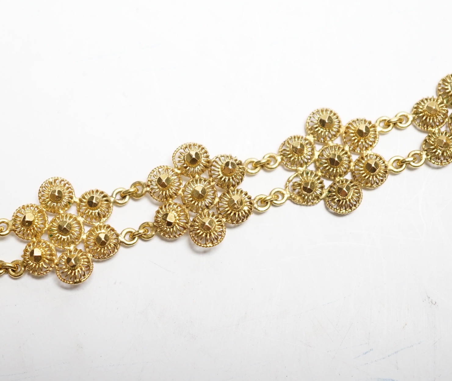 A yellow metal 'bright cut engraved' flower head link bracelet, 16cm, 14.7 grams.